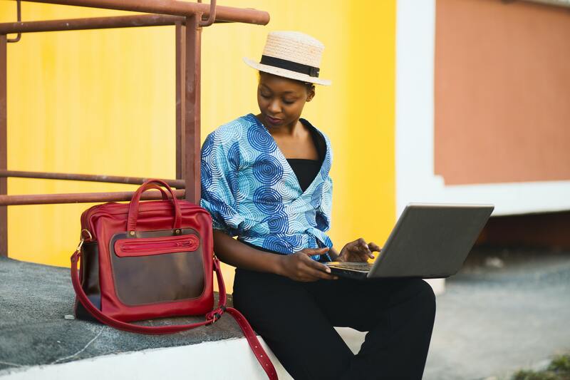 Who Is a Blogger and What Does It Take to Be One? Woman with a travel bag and a laptop